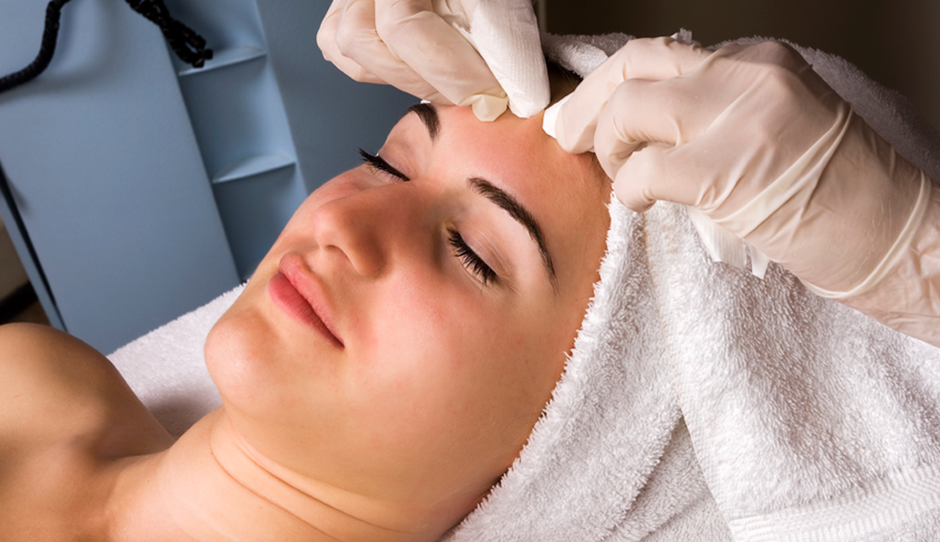 A woman lying down on a treatment bed receiving a professional facial at a skin studio.